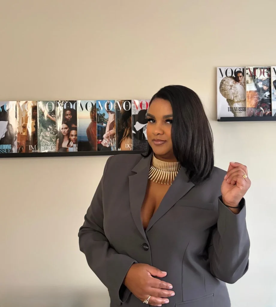 Jennifer Elmzoon in een grijze blazer voor een wand met Vogue-covers